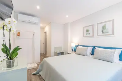 a white bedroom with a bed and a vase with flowers at Avenue 41 Guest House in Faro