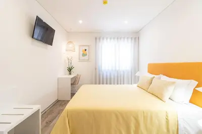 a hotel room with a yellow bed and a television at Avenue 41 Guest House in Faro