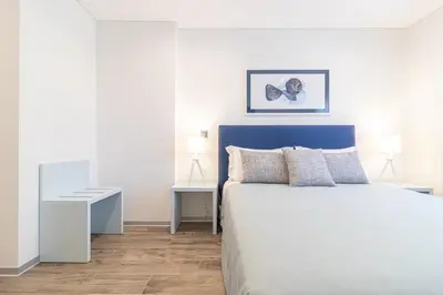 a bedroom with a bed with a blue headboard and two tables at Avenue 41 Guest House in Faro