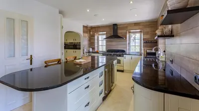 a large kitchen with white cabinets and a black counter top at Portuguese mansion close to marina, golf and beach. in Vilamoura