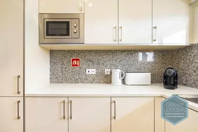 a kitchen with white cabinets and a microwave at Jardins da Marina - Dream Lodging in Albufeira