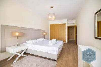 a bedroom with a bed with white sheets and a lamp at Jardins da Marina - Dream Lodging in Albufeira