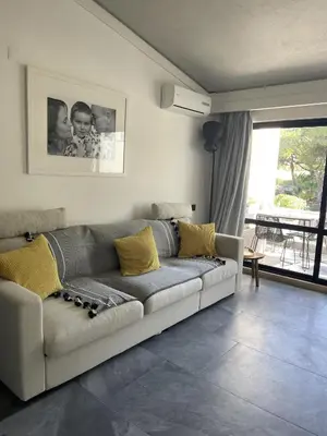 a living room with a gray couch with yellow pillows at Scarlet's Place - 1 bed Victory Village Quinta Do Lago - beach, nature, lakes in Quinta do Lago