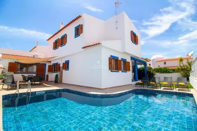 a villa with a swimming pool in front of a house at Villa Girassol - By Dalma Portuguesa in Albufeira