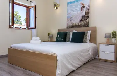 a bedroom with a large bed and a painting on the wall at Villa Girassol - By Dalma Portuguesa in Albufeira