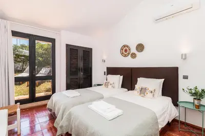 two beds in a white room with a window at Casas Barulho - Villa Jacaranda A8 in Albufeira