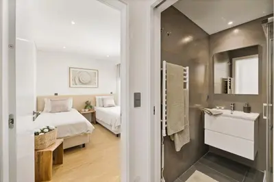 a bedroom with a bed and a bathroom with a sink at Stylish Modern Beachside Apartment with Pool & Seaview in Quarteira