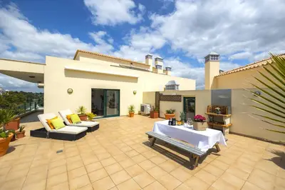 a patio with a table and chairs on a house at Penthouse Escape with Large Terrace, Pool & Garden in Quarteira