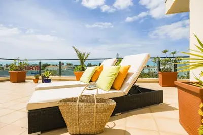 a bed on a balcony with a view of the ocean at Penthouse Escape with Large Terrace, Pool & Garden in Quarteira