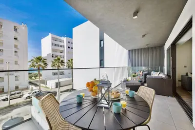 a dining table on the balcony of a apartment at Bright Modern Beachside Apartment with Pool & Seaview in Quarteira