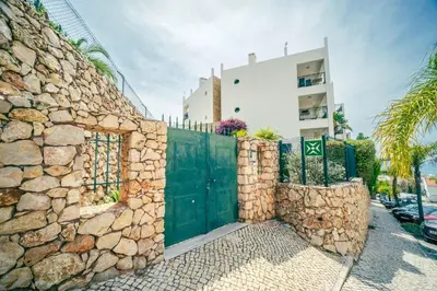 a stone fence with a green gate in front of a building at Albufeira - Cerro Mar Star - Cozy and Relaxing T1 in Albufeira