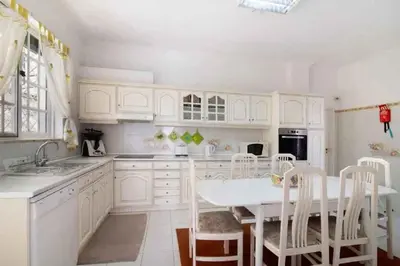a kitchen with white cabinets and a white table and chairs at Algarve Paraíso Casa Lagos e Relvas in Estói