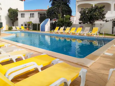 a swimming pool with yellow and white lounge chairs at Apartamento Tio Pedro - by bedzy in Albufeira