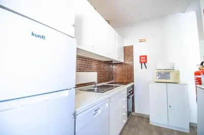 a kitchen with white cabinets and a sink and a microwave at Vilamoura Golf Studio With Pool by Homing in Vilamoura