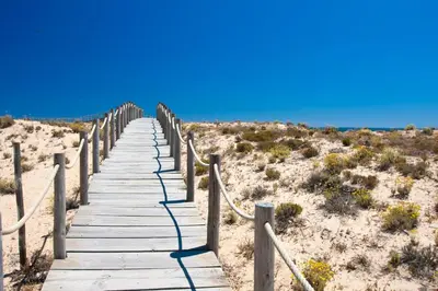a wooden boardwalk through the sand in the desert at Tulio 2 Bedroom Luxury Apartment located in Encosta Do Lago in Quinta do Lago