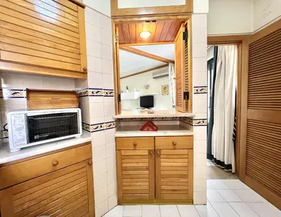 a kitchen with wooden cabinets and a microwave at Talia XII - Near the beach by HD PROPERTIES in Vilamoura