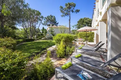 a patio with benches and an umbrella in a yard at Sera - Luxury 3 bedroom apartment with pool, golf,beach in Ludo