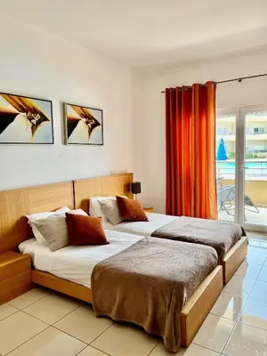 two beds in a bedroom with an orange curtain at Barracuda ByTheSea in Albufeira