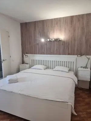 a bedroom with a large white bed and a wooden wall at AAA T2 Awesome Albufeira Apartments Piscina Marina in Albufeira