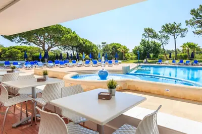 a patio with tables and chairs next to a swimming pool at Victory Village 10C in Quinta do Lago