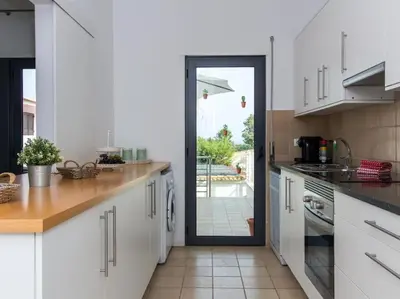 a kitchen with white cabinets and a sliding glass door at Rainbow House by Stay ici Algarve Holiday Rental in Albufeira