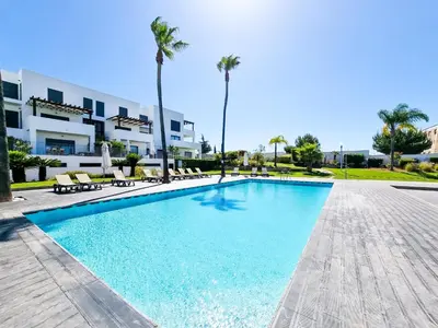 a swimming pool in front of a building with palm trees at FLH Vilamoura Villa Rosa Golf Apartment with Pool in Vilamoura