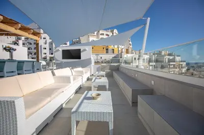 a balcony with white couches and tables on a building at Sun Lovers Hostel in Albufeira