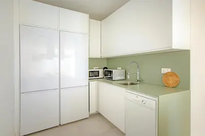 a white kitchen with white cabinets and appliances at Sun Lovers Hostel in Albufeira