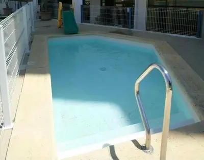 a large blue pool with a metal hand rail at 1 Bedroom Apartment Chaves, Praceta Vitorino Nemesio, Albufeira in Albufeira