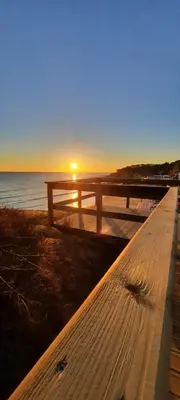 a bench on the beach with the sunset in the background at Lendas de Portugal in Olhos de Água