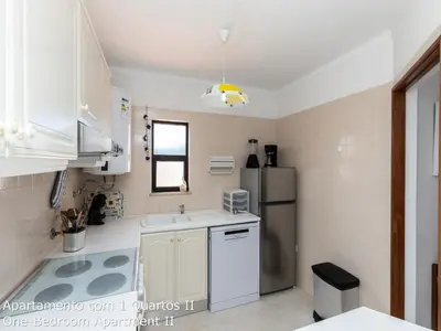 a kitchen with white cabinets and a refrigerator at Akisol Albufeira Sunny in Roja- Pé