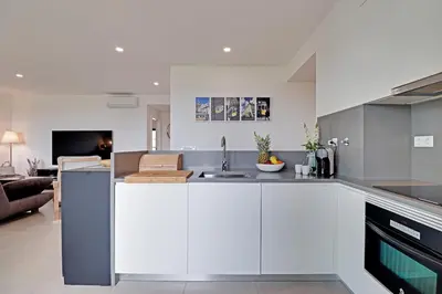 a kitchen with white cabinets and a living room at Andiamo Apartment in Vilamoura
