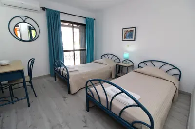 a room with three beds and a table and a table and chairs at Apartamento T2 Praia de São Rafael Hibiscus 41A - Albufeira, Algarve in Albufeira