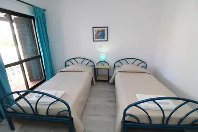 three beds in a room with a window at Apartamento T2 Praia de São Rafael Hibiscus 41A - Albufeira, Algarve in Albufeira