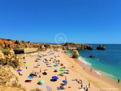 a group of people on a beach with umbrellas at Apartamento T2 Praia de São Rafael Hibiscus 41A - Albufeira, Algarve in Albufeira