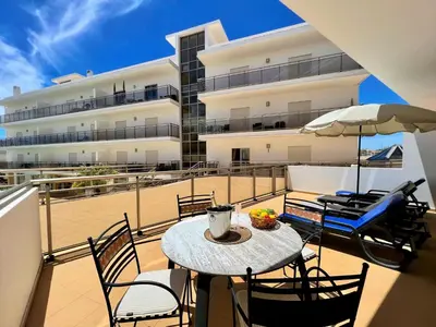 a balcony with a table and chairs and a building at Albufeira Terrace With Pool by Homing in Albufeira