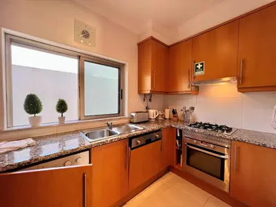 a kitchen with wooden cabinets and a sink and a window at Albufeira Terrace With Pool by Homing in Albufeira