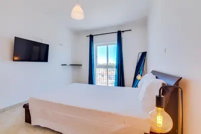 a bedroom with a large white bed with a window at AL - Quarteira Old Town in Quarteira