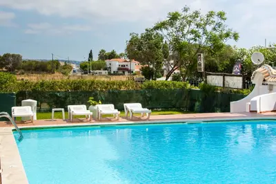 a swimming pool with white chairs and a swimming pool at Açoteias B3 in Albufeira