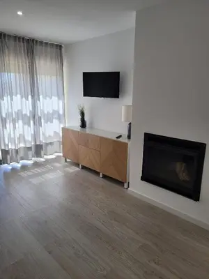 a living room with a fireplace and a flat screen tv at Apartamento T1 Salgados in Guia