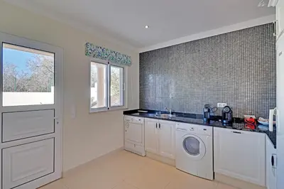 a kitchen with a washer and dryer and a window at Casa do Pomar by Portucasa in Alte