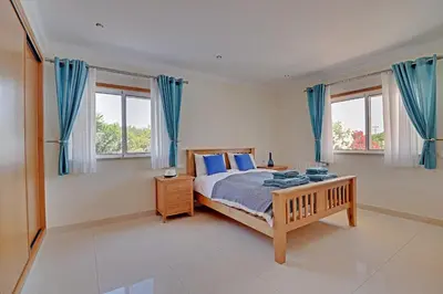 a bedroom with a large bed with blue curtains at Casa do Pomar by Portucasa in Alte