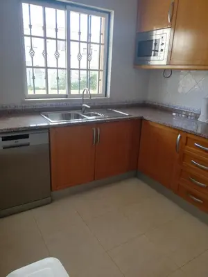a kitchen with wooden cabinets and a sink and a window at Villa V2 U in Olhos de Água