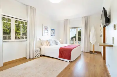 a white bedroom with a bed and windows at Vila Santa Eulália in Albufeira