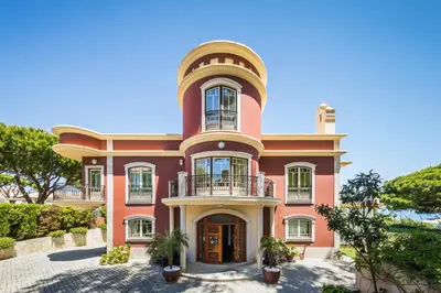 a large pink house with a round turret at Vila Santa Eulália in Albufeira