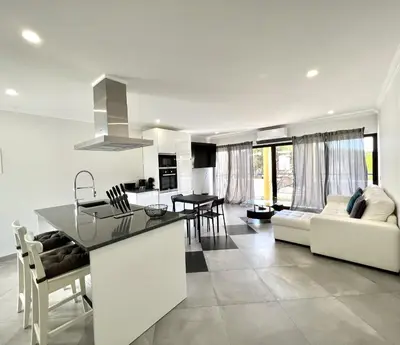 a white kitchen and living room with a white couch at Topazio - Pool & near the center by HD PROPERTIES in Vilamoura
