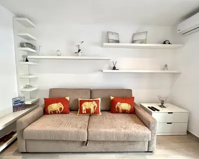 a couch in a living room with white shelves at Beachside Apartment - With Pool by HD PROPERTIES in Quarteira