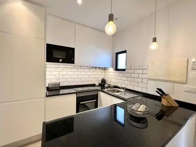 a kitchen with a black counter top and white cabinets at Beachside Apartment - With Pool by HD PROPERTIES in Quarteira