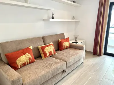 a couch with orange pillows in a living room at Beachside Apartment - With Pool by HD PROPERTIES in Quarteira