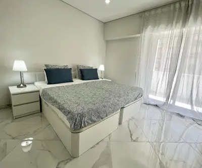 a white bedroom with a large bed with blue pillows at Aman - Near the beach by HD PROPERTIES in Quarteira